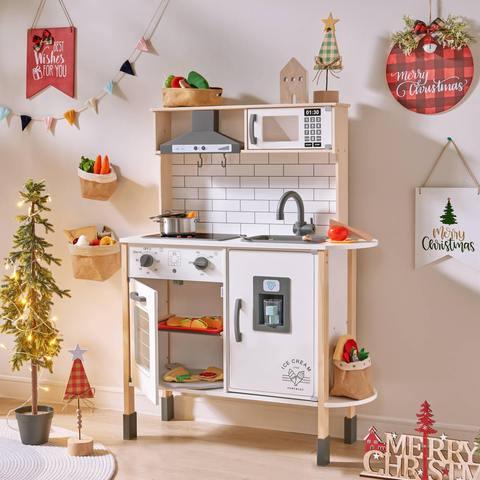 A white kitchen with beautiful Christmas decorations is placed in the playroom.