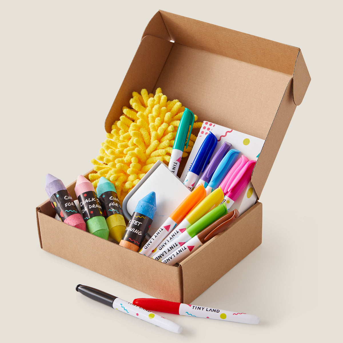 The Tiny Land® Magnitales Easel Art Kit by Tiny Land includes colorful markers, chalk-shaped crayons, a yellow fuzzy cloth, sticky notes, and extra markers—perfect for kids’ art projects or as whiteboard and chalkboard supplies.