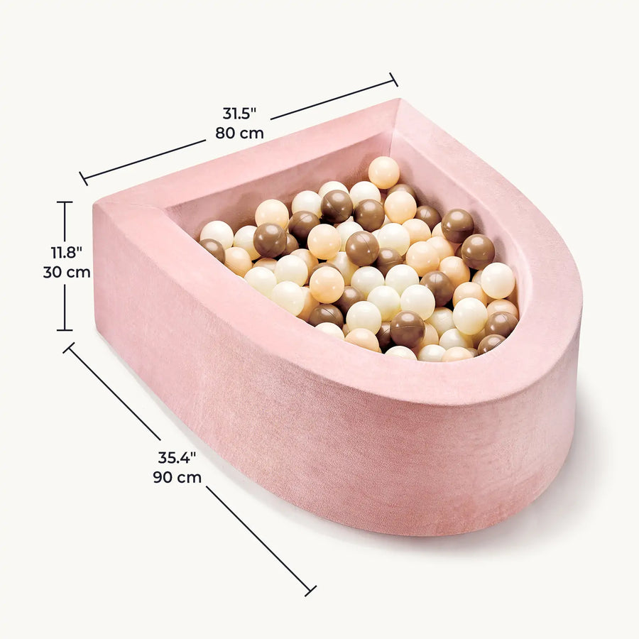 The Tiny Land® PlayNest Ball Pit by Tiny Land features pink velvet, a semi-circular foam design (35.4" x 31.5" x 11.8"), and comes with 200 beige, cream, white, and brown ocean balls—perfect for a cozy toddler play space.|Pink