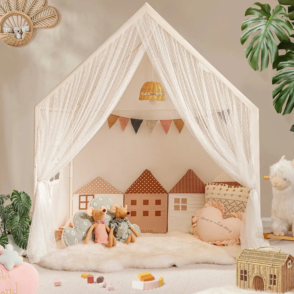 The Tiny Land® Chef’s Corner Playset features a cozy cream playhouse and kitchen set, complete with sheer white curtains, house-shaped pillows, stuffed animals, soft rugs, toys, and plants in a warmly decorated room.|mesh