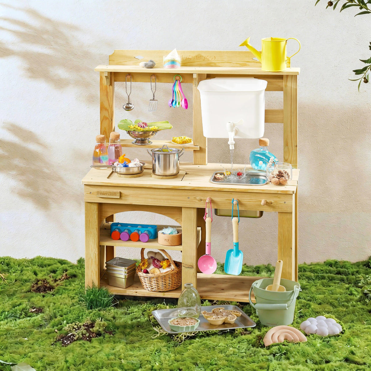 The Tiny Land® Outdoor Mud Kitchen & Sand Play Set by Tiny Land is set on grass and comes with toy pots, pans, utensils, cups, a plastic sink, yellow watering can, play food baskets, jars, and a sand toy set for imaginative outdoor fun.