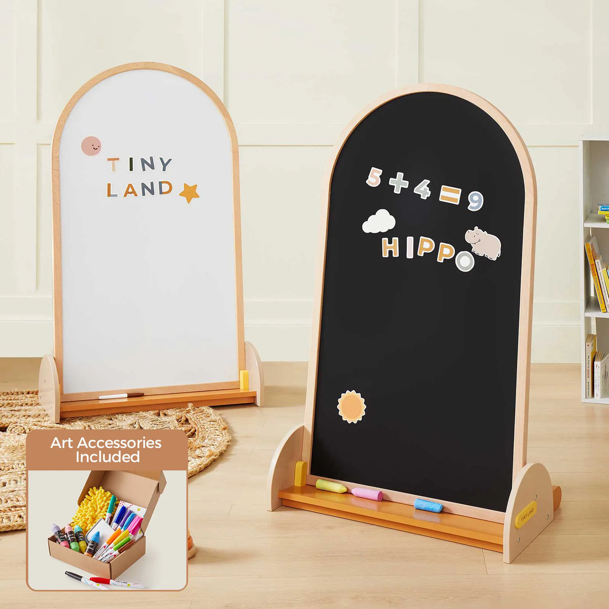 Two wooden-framed easels—a whiteboard on one side and a blackboard on the other—stand side by side with colorful chalk. The Tiny Land® Double-Sided Arched Magnet Chalkboard & Art Kit is perfect for young artists, and an inset shows the included kids' art accessory kit featuring markers, erasers, and chalk from Tiny Land.