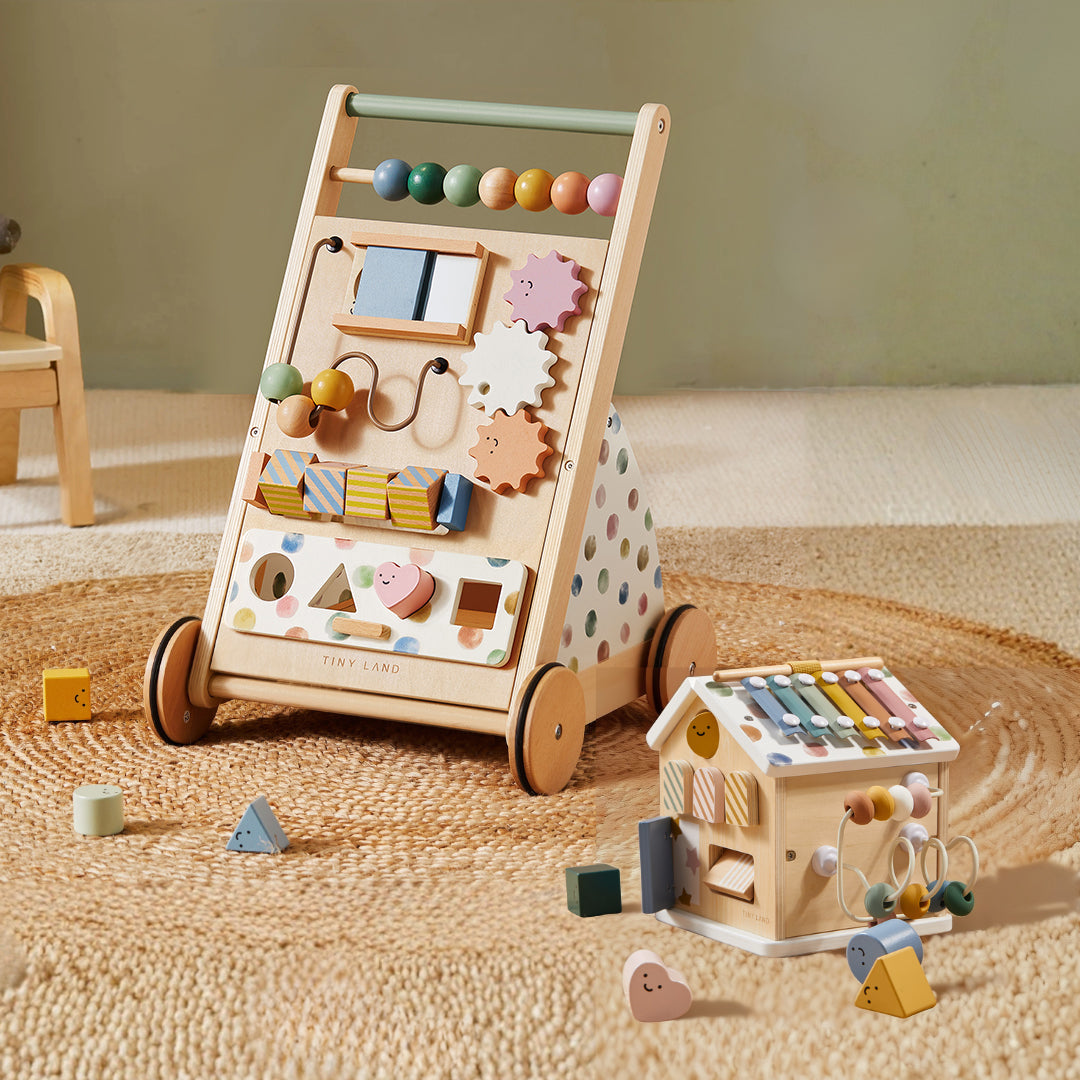 The Tiny Land Complete Development Playset — Baby Walker + Activity Cube rests on a woven rug beside scattered colorful blocks in a cozy playroom, creating an inviting space that fosters fine motor skill development through engaging activities and thoughtful design.