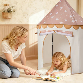 A woman sits on the floor beside a young girl lying on a rug inside the Tiny Land® Cheerful Pennant Castle Tent. She points to an open book, surrounded by soft lighting and light colors in this cozy Tiny Land playhouse scene.|Brown