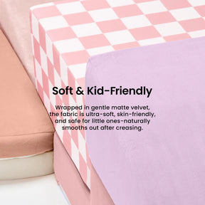 A close-up of a children's mattress with pink and white checks, lavender sheet, and beige-pink cushion. Text: Soft & Kid-Friendly—perfect for pairing with Tiny Land® PlayNest Climbing Blocks or other toddler climbing toys.