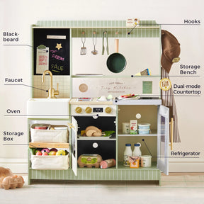 The Tiny Land® BistroSwitch Play Kitchen by Tiny Land features labeled parts such as a blackboard, faucet, oven, storage box, hooks, storage bench, dual-mode countertop, and a refrigerator stocked with play food and utensils. This play kitchen set inspires endless imaginative fun and realistic role-play for exciting pretend kitchen adventures.|Green