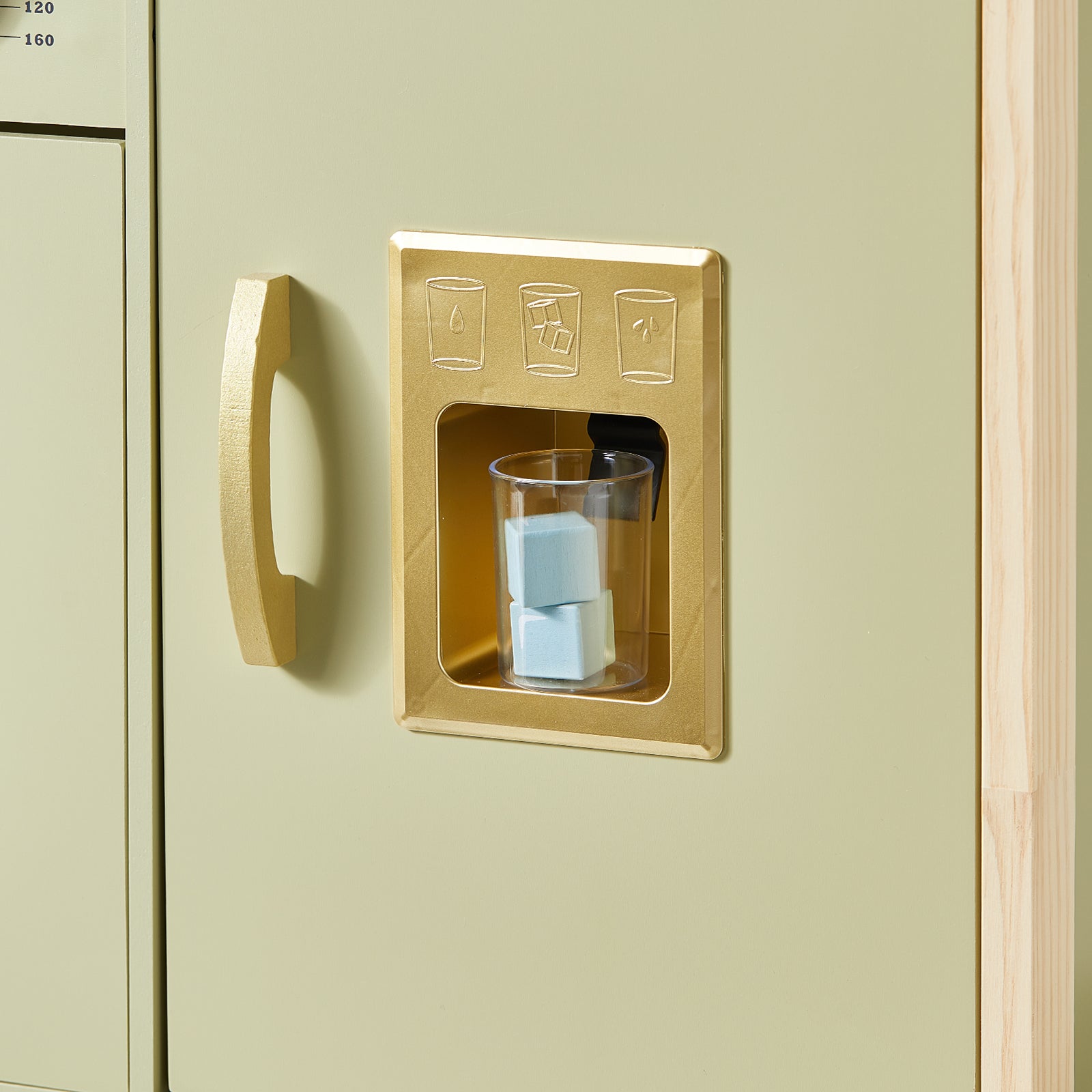 A plastic cup with blue toy ice cubes sits in a gold-colored pretend ice dispenser on the Tiny Land® PopJoy Play Kitchen - Green by Tiny Land.