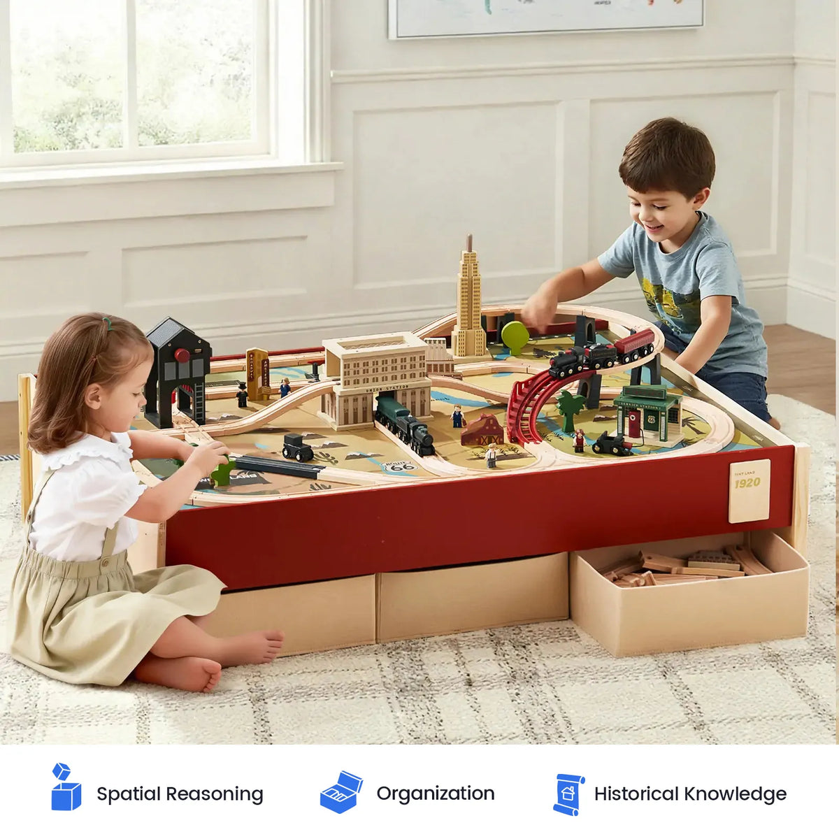 Two young children enjoy imaginative play with the Tiny Land® 1920 Railway Adventure Train Table by Tiny Land, featuring interactive details and intricate 1920s city buildings atop a spacious, elevated table with built-in drawers. The bright room is decorated with framed artwork. Skill icons below showcase benefits such as spatial reasoning, organization, and historical knowledge.