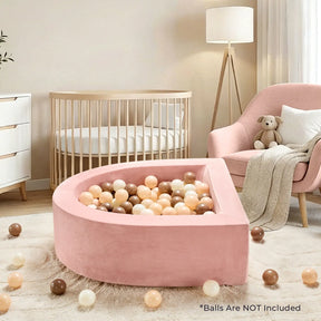 A cozy nursery with a Tiny Land® PlayNest Ball Pit (ocean balls not included) in pink, pastel and brown balls, a pink armchair with teddy bear, wooden crib, lamp, and white dresser by Tiny Land in the background.|pink