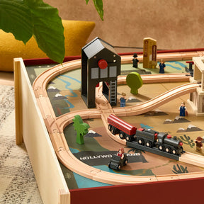 The Tiny Land® 1920 Railway Adventure Train Table by Target features interactive tracks, a black train with red accents, trees, buildings, figurines, and “HOLLYWOODLAND” printed on the play table for a vintage city vibe.