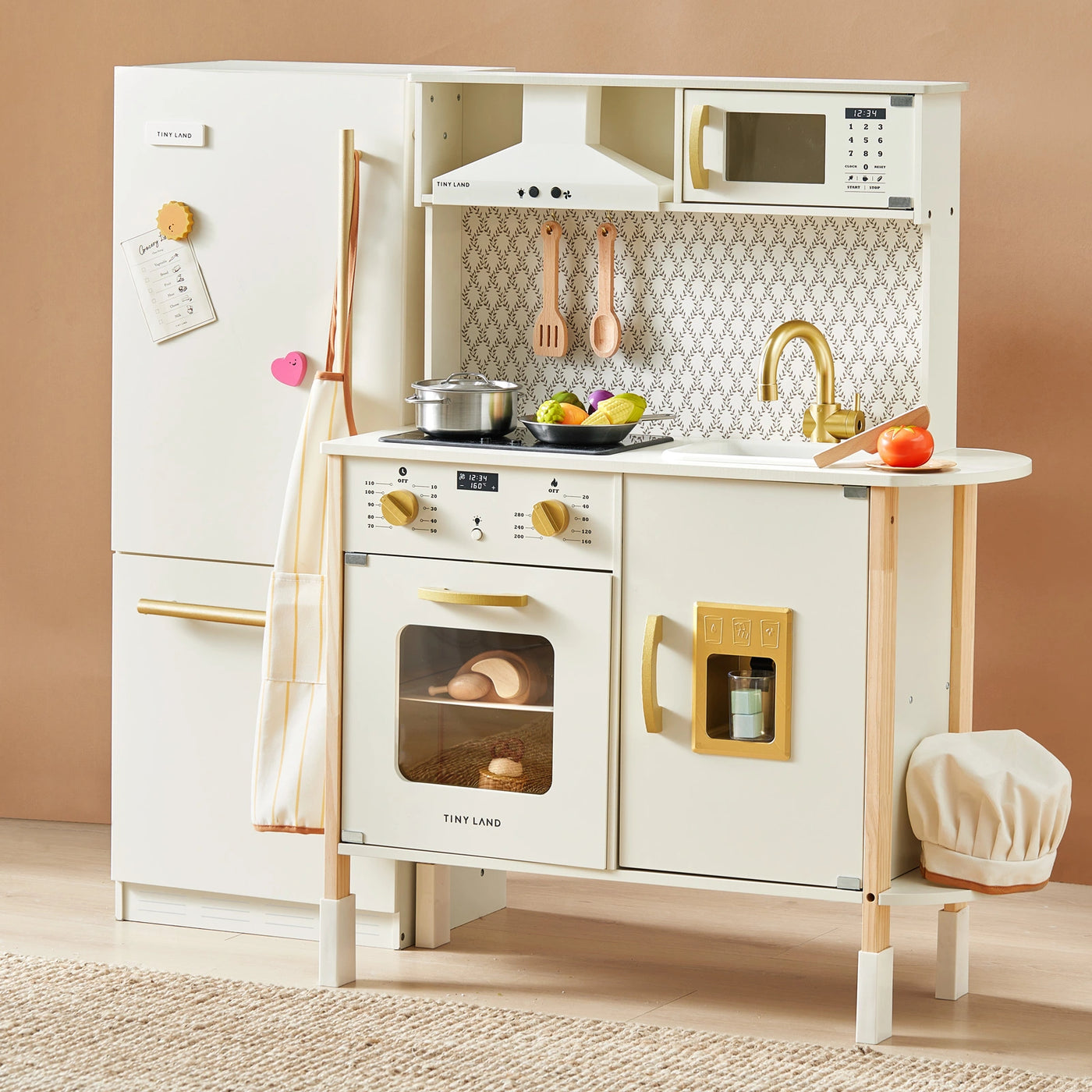 The Tiny Land® PopJoy Kitchen & Fridge Set by Tiny Land includes a fridge, oven, microwave, sink, stove, utensils, play food, chef hat, and cookware in a stylish white and gold design with realistic details for pretend play.