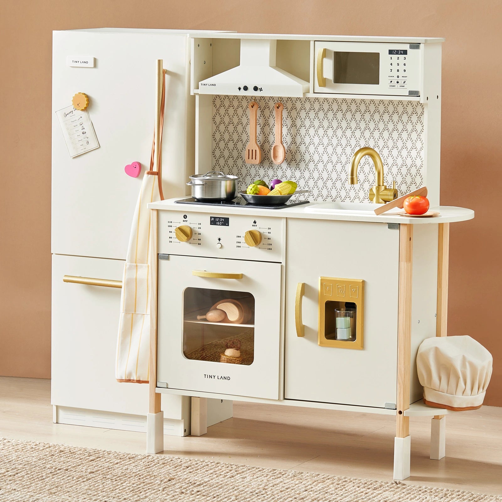 The Tiny Land® PopJoy Kitchen & Fridge Set by Tiny Land includes a fridge, oven, microwave, sink, stove, utensils, play food, chef hat, and cookware in a stylish white and gold design with realistic details for pretend play.