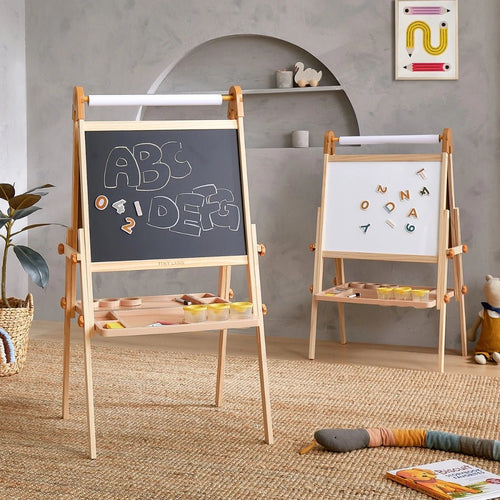 Two Tiny Land® Caramel Magnitales Easels for Kids are in a playroom—one features a chalkboard with 