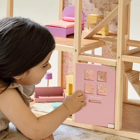 A young child plays with the Tiny Land® Sweetwood Unicorn Dollhouse by Tiny Land, opening a small pink door. This wooden dollhouse includes miniature furniture, poseable dolls, and a charming staircase inside.|Unicorn