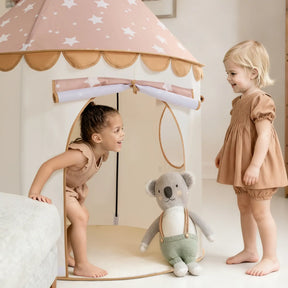 Two young children play near the Tiny Land® Cheerful Pennant Castle Tent by Tiny Land. One smiles inside the kids’ playhouse while the other stands outside. A plush koala toy is placed at the tent’s entrance.|Brown
