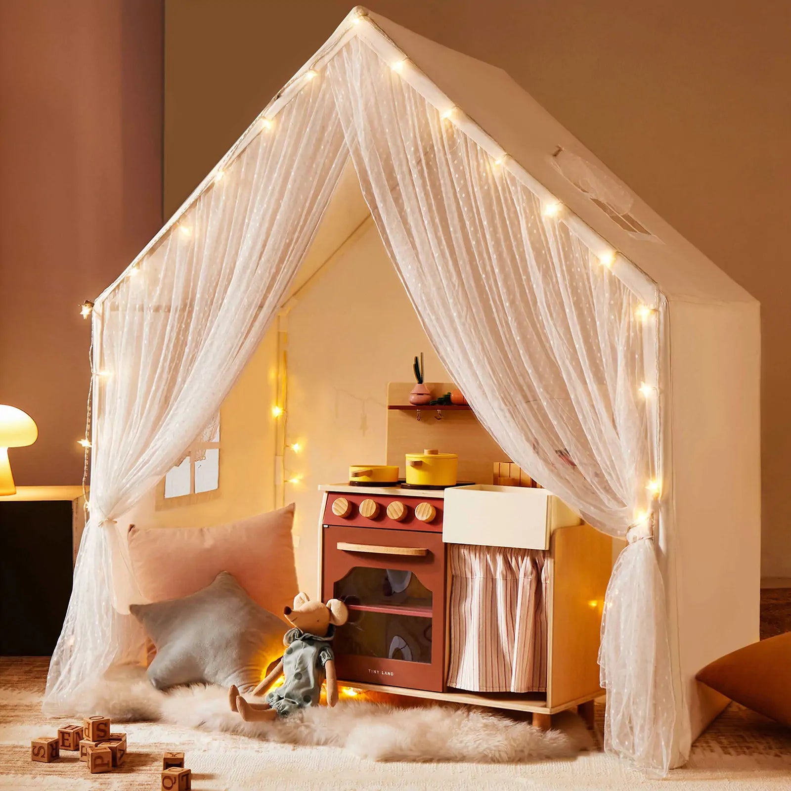 The Tiny Land® Large Space Play House with Star Lights by Tiny Land is a cozy kids’ playhouse featuring string lights, sheer curtains, a toy kitchen, plush cushions, soft rug, wooden blocks, and a stuffed mouse for inviting play.|mesh