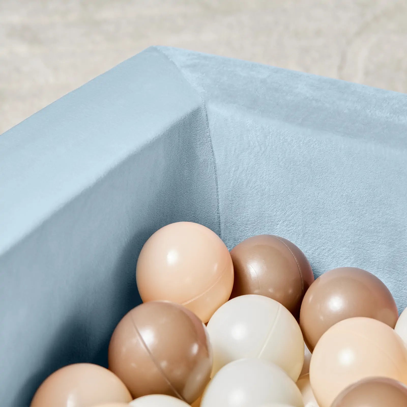 A close-up of the Tiny Land® PlayNest Ball Pit with 200 ocean balls in cream, beige, and light brown by Tiny Land, crafted from high-density foam and placed on a light-colored surface.