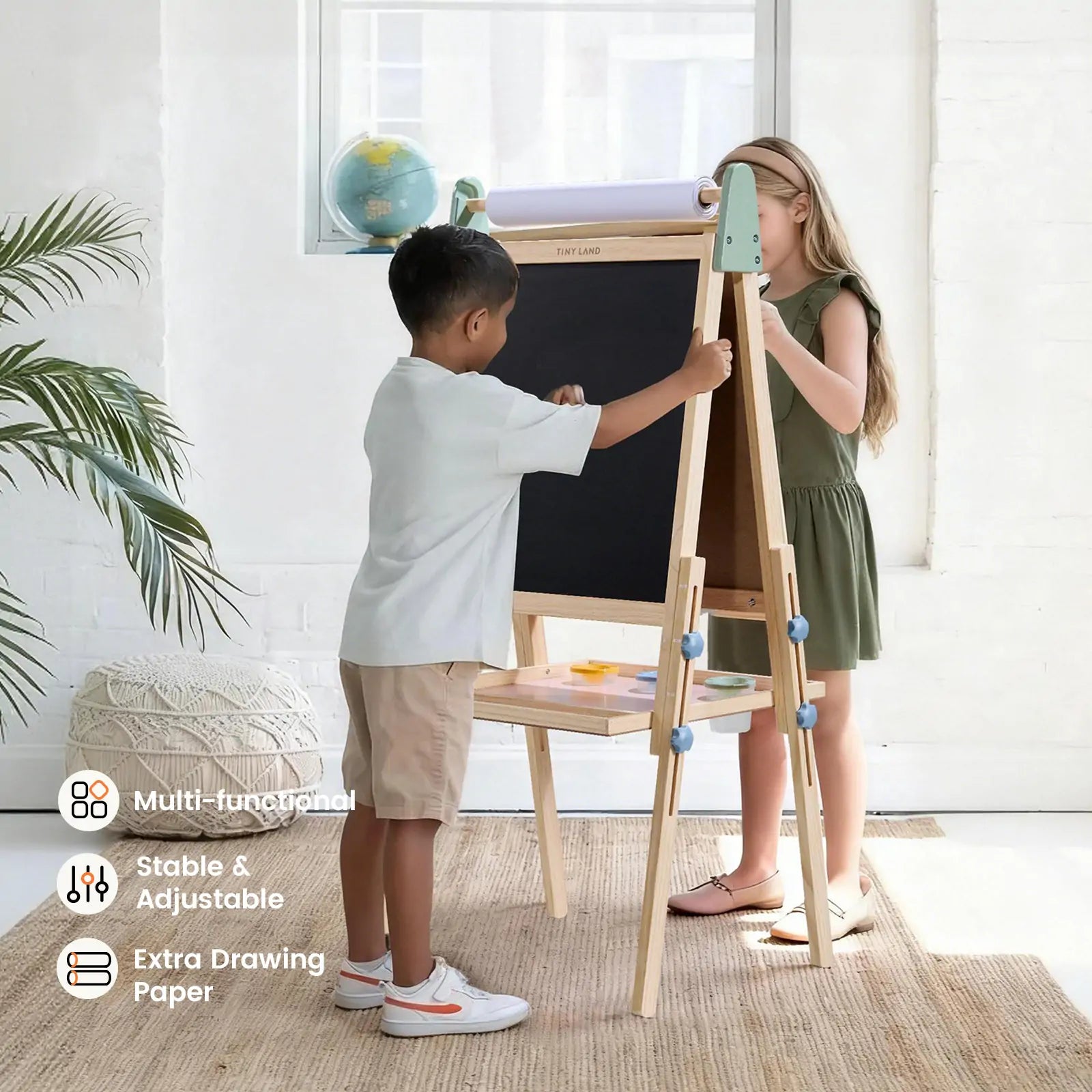 Two children, a boy and a girl, draw on the Tiny Land® 3-in-1 Art Easel for Kids - Morandi in a bright room. This double-sided easel by Tiny Land features a blackboard, paper roll, shelf, and icons showing its multifunctionality and extra drawing paper.|green