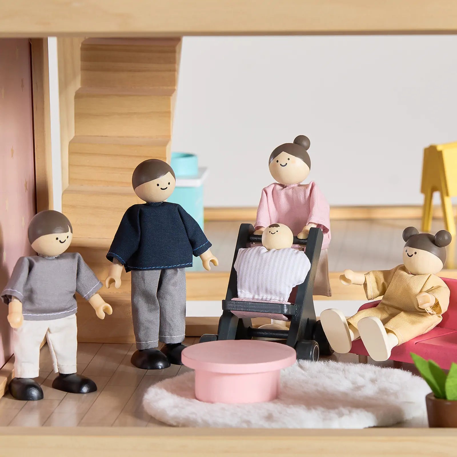 The Tiny Land® Sweetwood Love Dollhouse features a cozy living room with four wooden dolls, a baby in a stroller, modern furniture, pink table, stairs, and a green plant—perfect for imaginative play by Tiny Land.