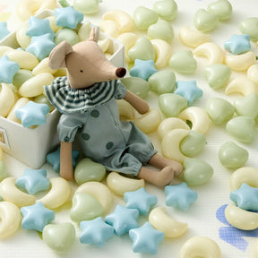 A fabric mouse doll in blue sits beside a box of Tiny Land® Fun-Shapes Ocean Ball (200 pcs) by Tiny Land, featuring yellow heart and blue star non-toxic play balls scattered across a light surface.|Fun-Shapes