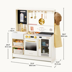 Introducing the Tiny Land® BistroSwitch Kitchen & Fridge Set by Tiny Land—a wooden kids’ play kitchen featuring gold handles, hanging utensils, a chef’s hat, striped apron, baskets, sink, stove, oven, and microwave. Measurement lines in black and gold display height, width, and depth in both inches and centimeters—making this interactive toy kitchen ideal for imaginative pretend play adventures.