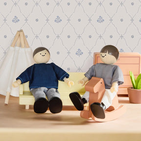 Two Tiny Land® Wooden Dollhouse Dolls from Tiny Land relax in a miniature living room with a yellow sofa, peach rocking horse, patterned wallpaper, small plant, and white teepee.