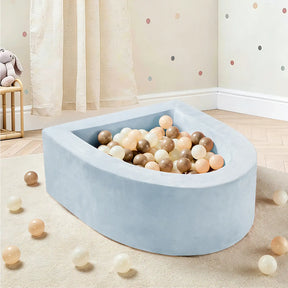 The Tiny Land® PlayNest Ball Pit with 200 Ocean Balls by Tiny Land, in light blue semi-circular design, is featured in a child's room with wooden floors, a curtain, polka-dot wall decor, and a stuffed rabbit on a stool.