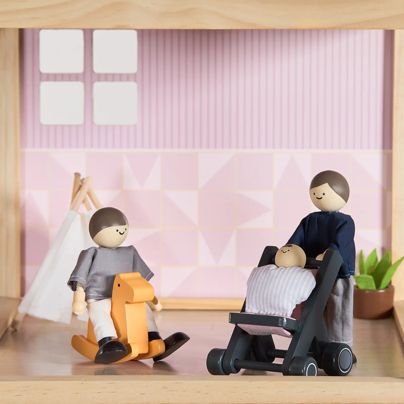 A Tiny Land® Sweetwood Love Dollhouse & Wooden Dollhouse Dolls set features a wooden doll family with a stroller, baby, and rocking horse, plus dollhouse furniture in rooms with pink and white walls, window, teepee, and plant.