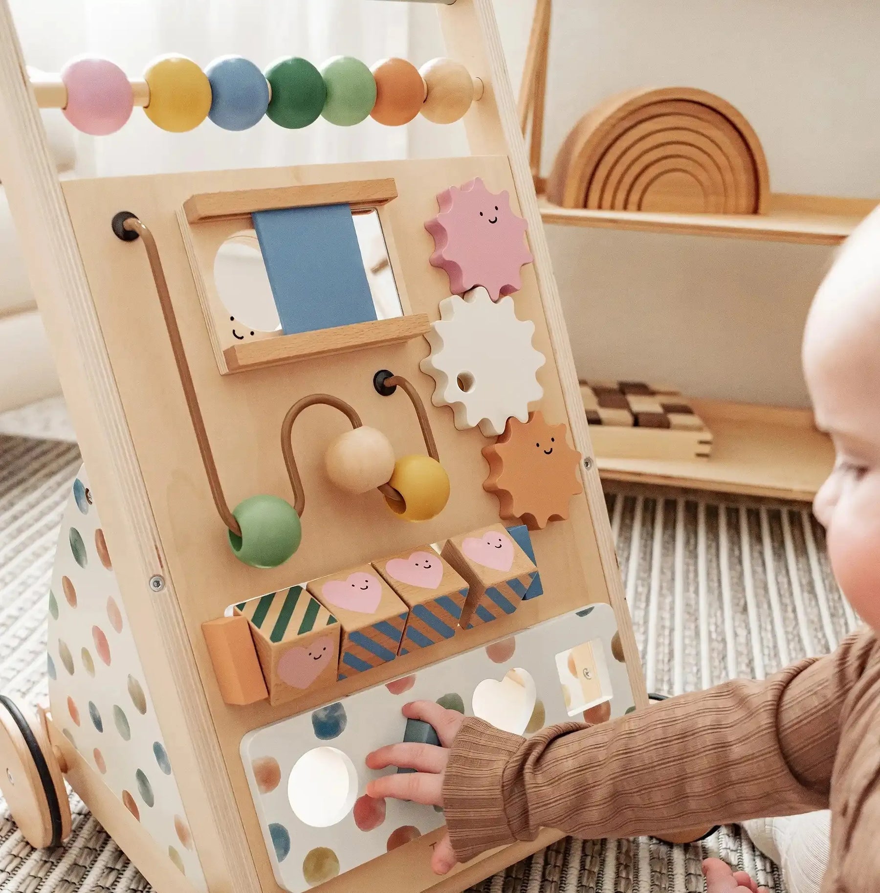 A baby enjoys exploring the Tiny Land Complete Development Playset — Baby Walker + Activity Cube on a carpeted floor, interacting with its colorful beads, gears, blocks, and mirror to build fine motor skills in a fun and Montessori-inspired way.