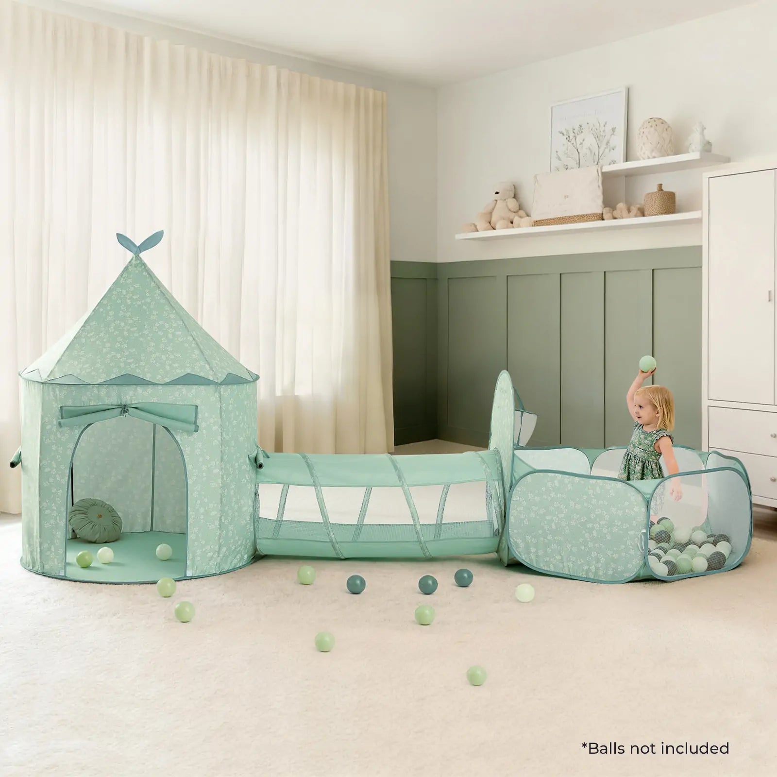 A young child enjoys the Tiny Land® Compact Adventure 3-in-1 Play Tunnel in green—a cozy, mint-green play tent and tunnel set—inside a softly lit room with green paneling, plush carpet, and stuffed animals on a shelf.|green