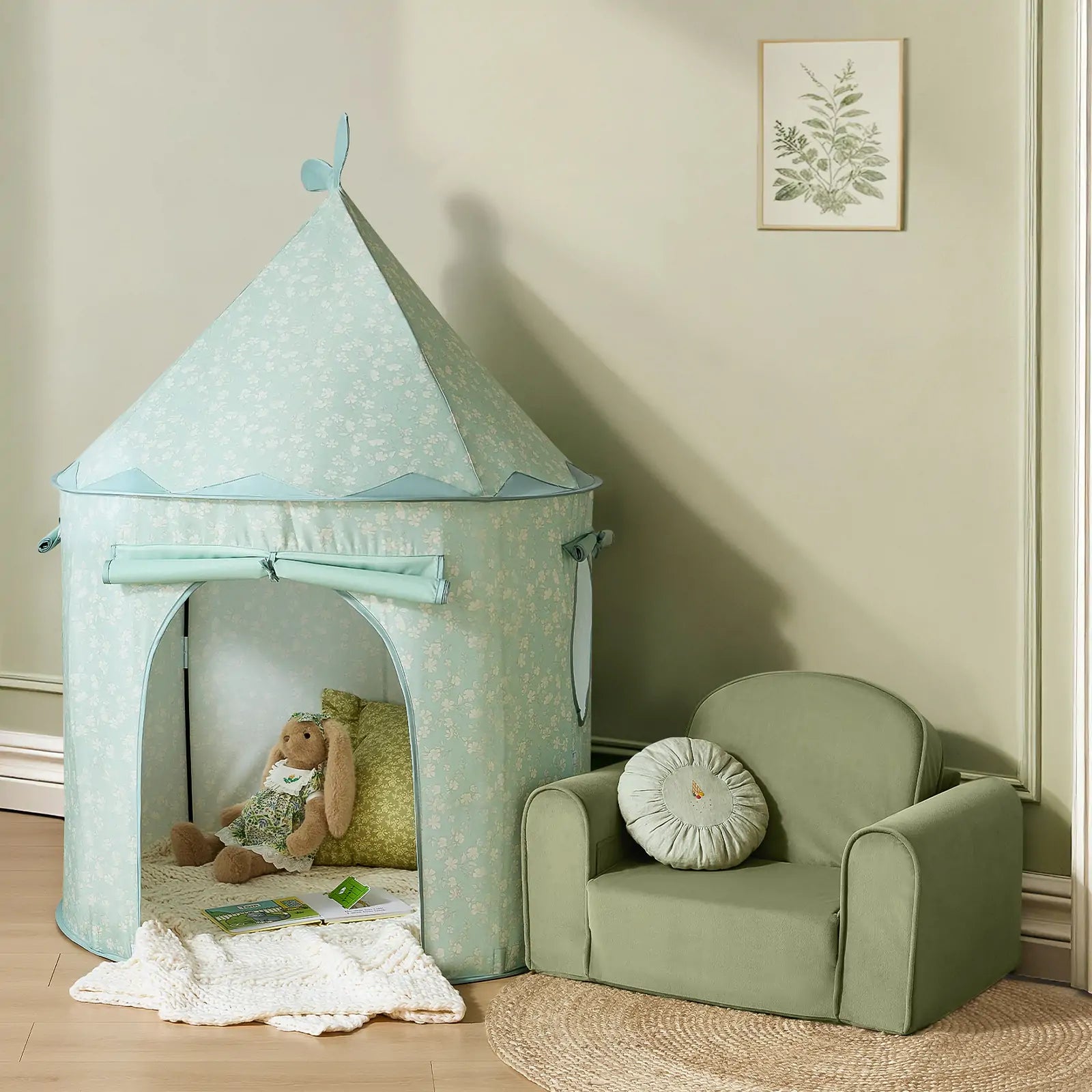 A cozy kids' play area features the Tiny Land® Tiny Sprout Castle Tent—with a stuffed rabbit and pillow inside—set beside a green armchair on a round woven rug, and accented with a botanical picture on the wall.|Green