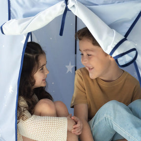 Two children smile as they sit inside the Tiny Land® Kids Tent – Indoor Tent for Toddlers by Tiny Land, a cozy blue play tent with white stars, perfect for playful moments in their indoor playhouse.|Blue