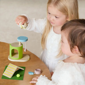 Two young children enjoy pretend play with the Tiny Land® Happy Urban Paws wooden pet play set. One holds a bee figurine above the hive while the other watches, both engaged in their mini pet paradise by Tiny Land.