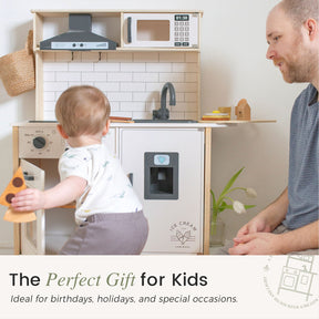A toddler enjoys the Tiny Land® Interactive Play Kitchen with Sounds & Cookware as an adult watches. Featuring a stove, sink, microwave, and ice cream machine—The Perfect Gift for Kids by Tiny Land for birthdays, holidays, and special occasions.