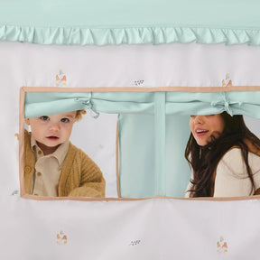 A baby and a woman smile while looking through the rectangular window of the Tiny Land® Sweet Woodland Kids Play Tent, featuring blue curtains, animal illustrations, and a cozy play mat for added comfort.|green