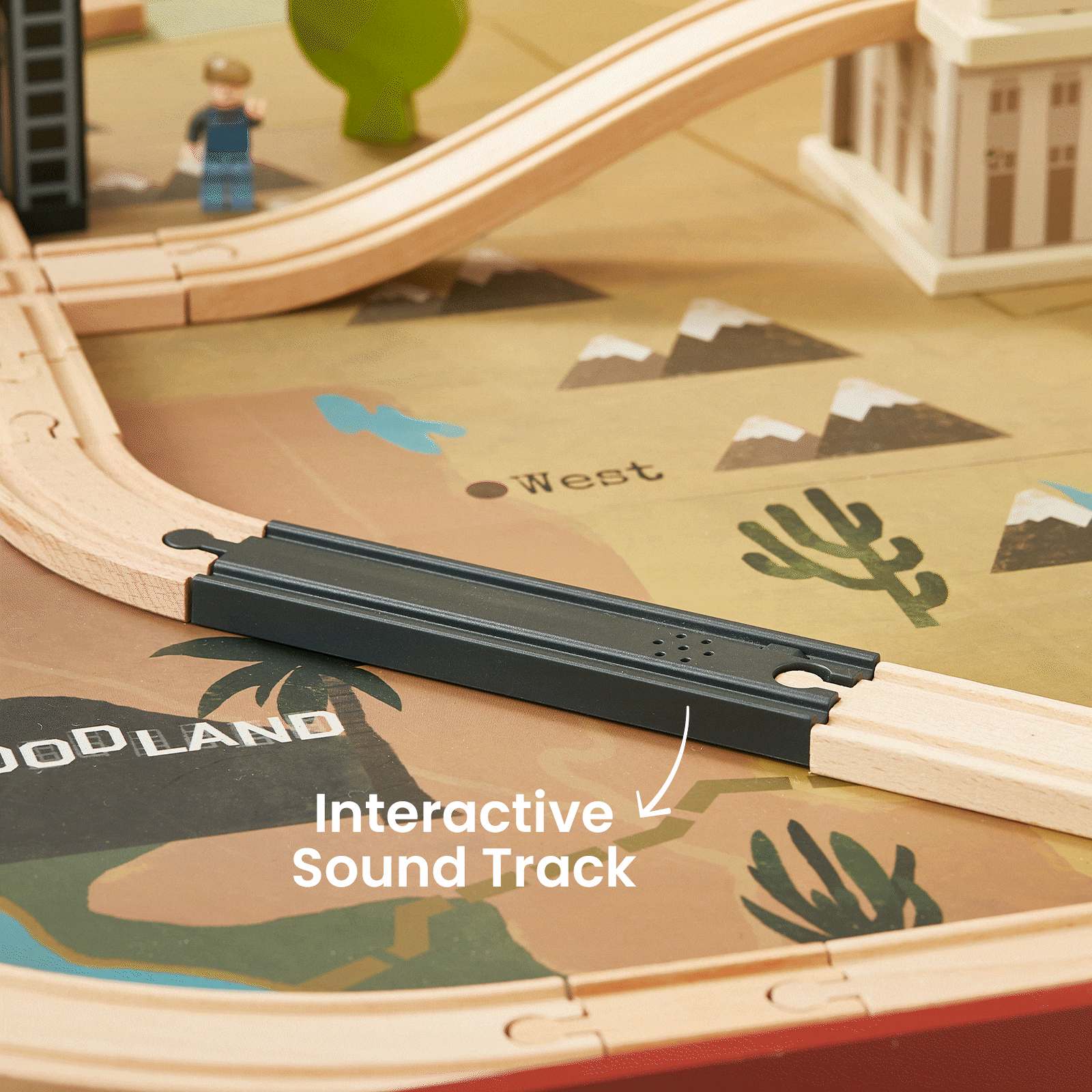 The Tiny Land® 1920 Railway Adventure Train Table features interactive elements like a black "Interactive Sound Track" piece, plus toy figures and scenery for imaginative play on a lively branded playmat.