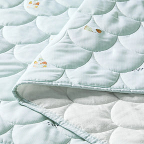 A close-up of the Tiny Land® Sweet Woodland Kids Play Tent quilt by Tiny Land, light blue with a scallop pattern and colorful butterflies. Partially folded to reveal its soft, dotted white lining—ideal as a play mat for your indoor tent.|green