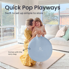 A woman and a smiling girl kneel on a light rug, holding a blue Tiny Land carry bag. Text: Tiny Land® Adventure 3-in-1 Play Tunnel & Ocean Ball Set – Blue. Quick to set up and store in the convenient carry bag.|blue