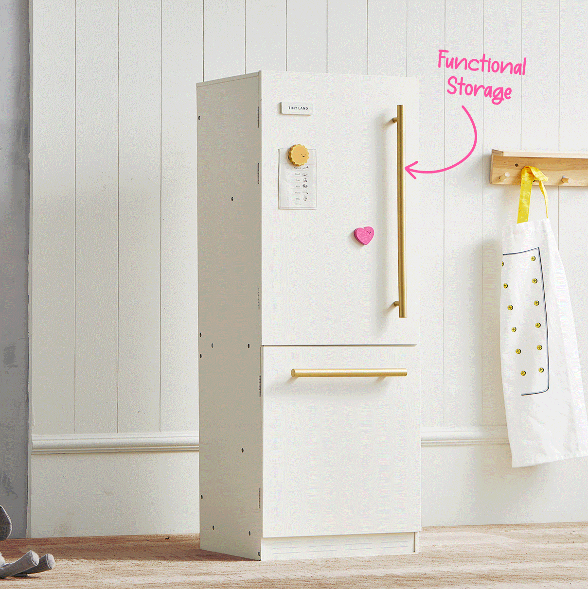 The Tiny Land® Farm-to-Table Play Set features a modern white wooden kitchen with gold handles and a labeled storage fridge. Ideal for pretend play, this interactive set by Tiny Land includes an apron and organic food collection.