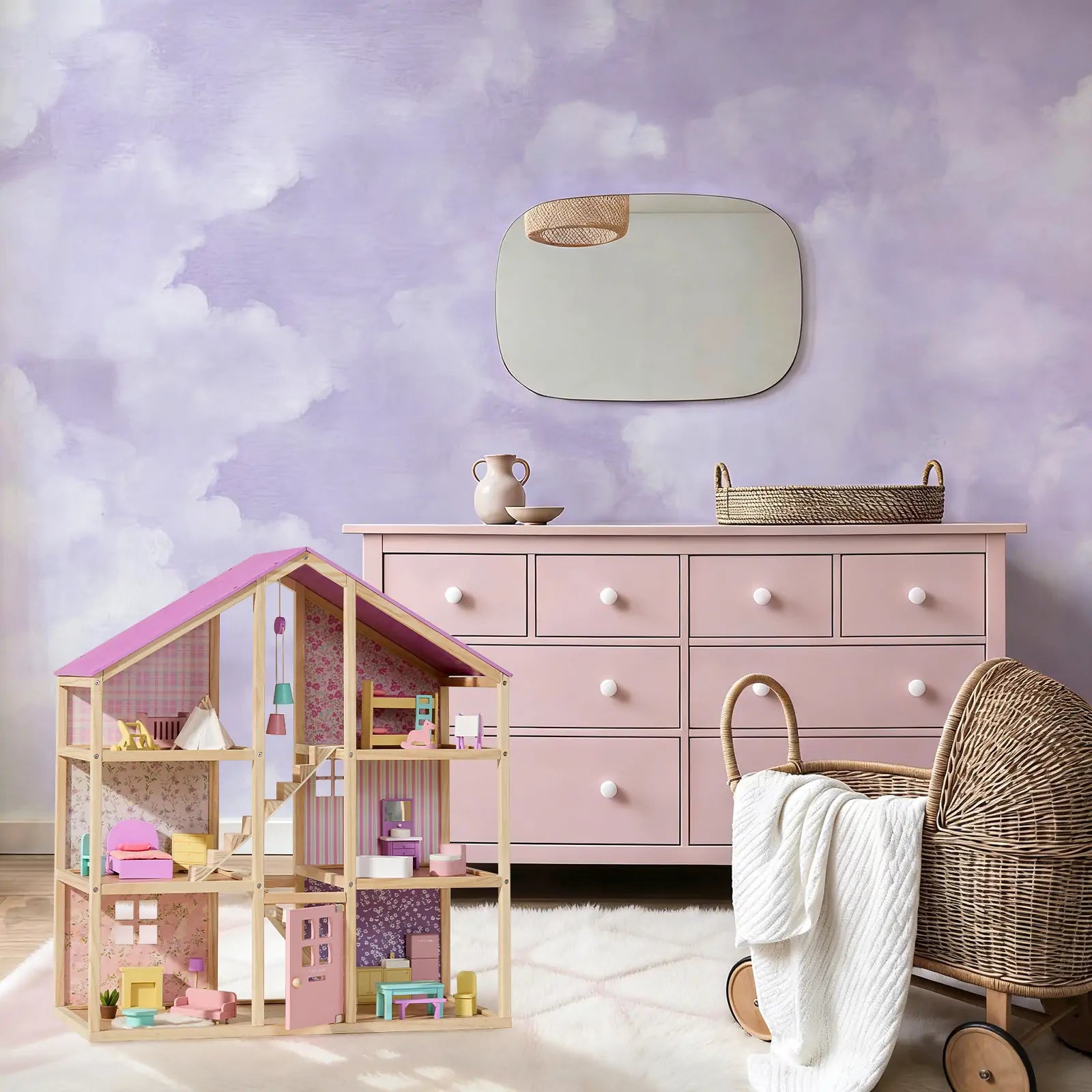 A pastel-themed child’s room featuring a pink dresser, Tiny Land® Sweetwood Unicorn Dollhouse & Wooden Dollhouse Dolls, a wicker bassinet with a white blanket, and a mirror on a cloud-painted purple and white wall.|Unicorn