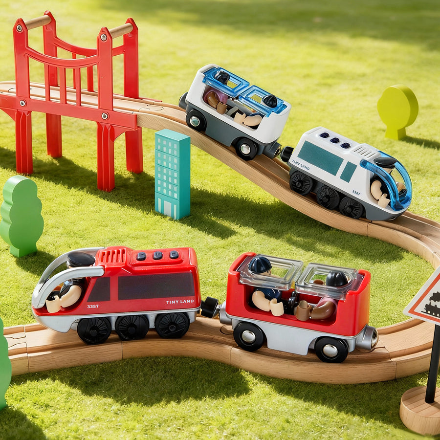The Tiny Land® Dual-Color Electric Toy Train by Tiny Land features colorful carriages, a curving wooden track with a red bridge, and a scenic green play mat, inspiring hours of imaginative interactive play.
