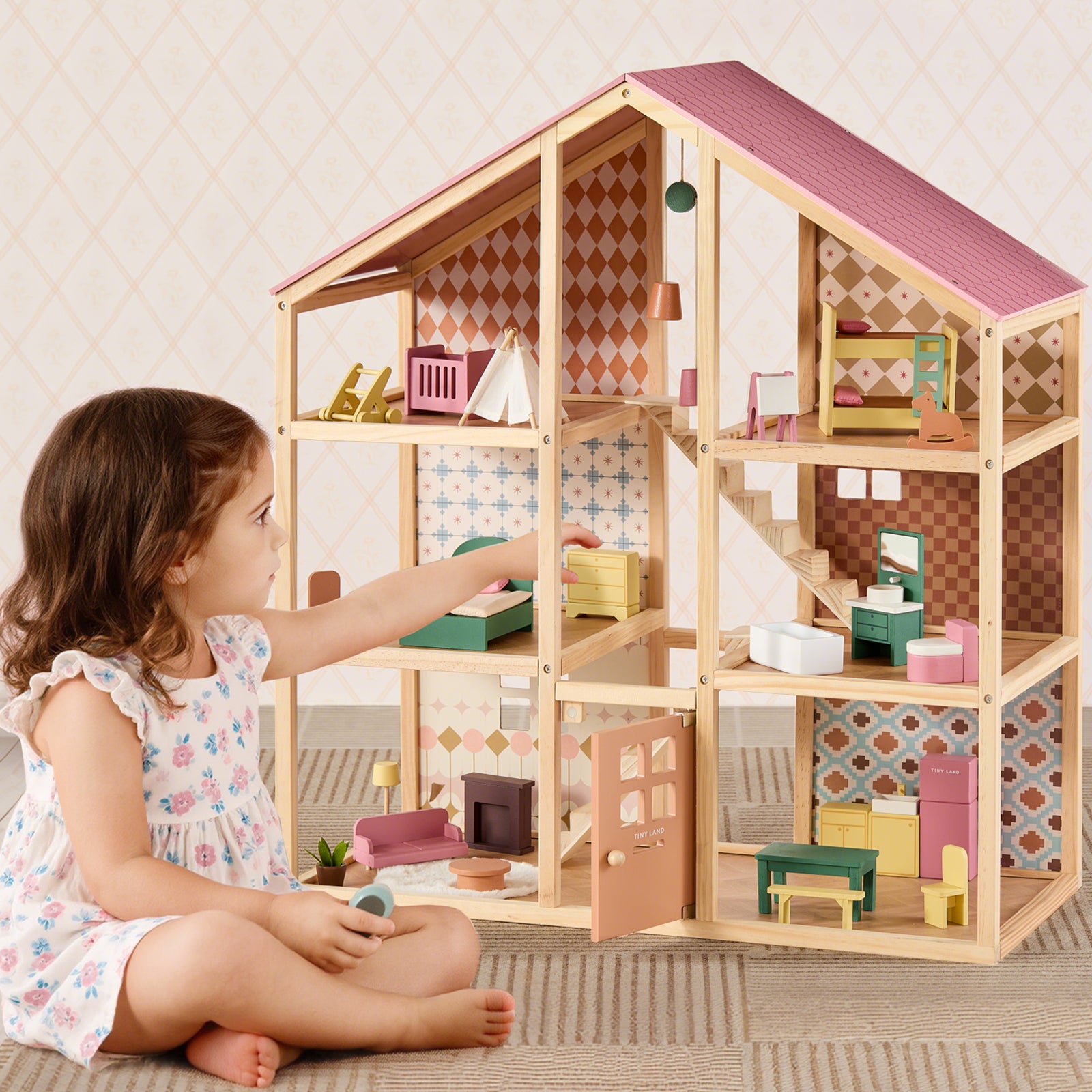 A young girl in a floral dress sits on the floor, arranging colorful furniture and decor in each charming room of her Tiny Land® Sweetwood Dollhouse without Dolls by Tiny Land, immersed in imaginative play.|Pegasus
