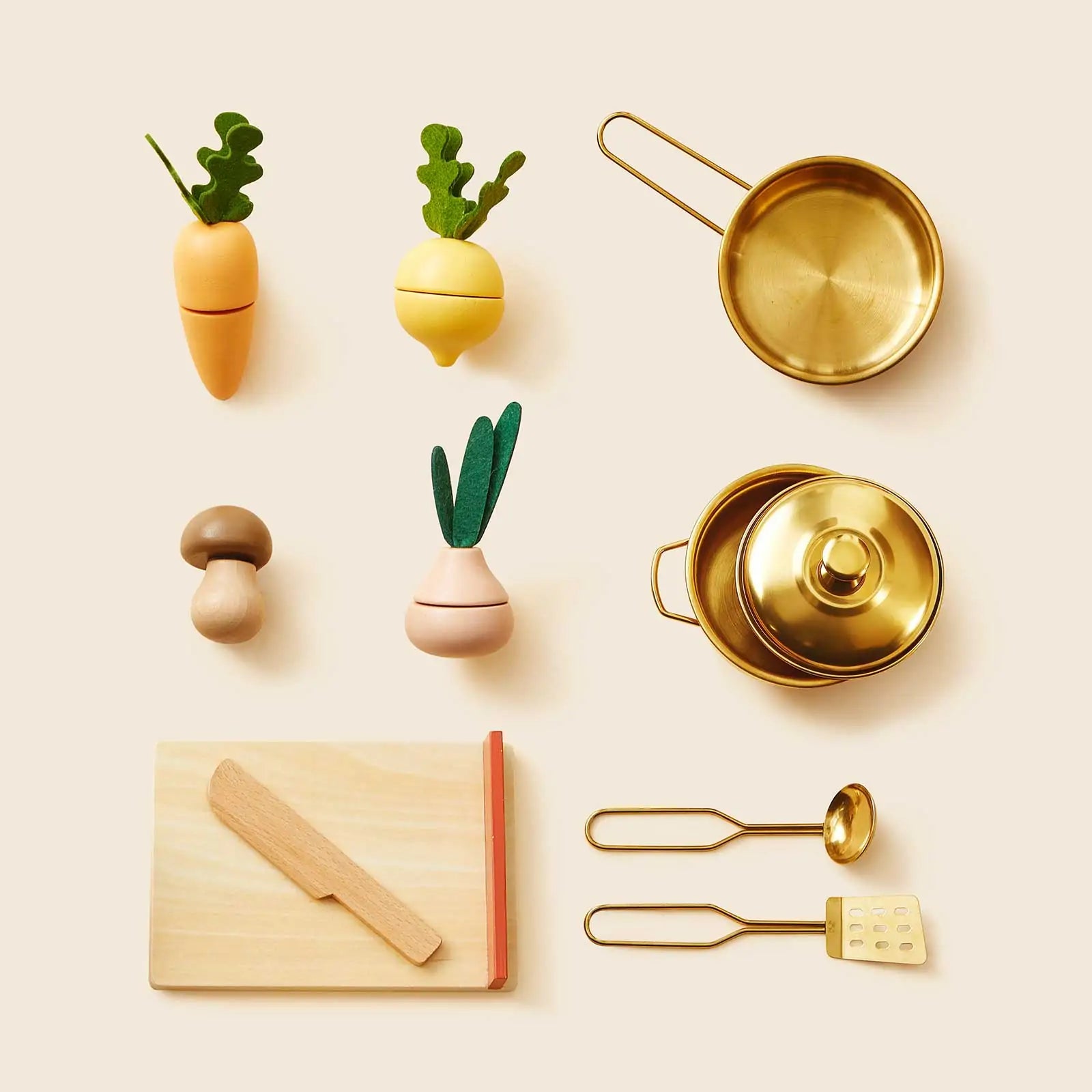 The Tiny Land® Mediterranean Play Kitchen by Tiny Land includes a cutting board, knife, spatula, mushroom, three veggies, two gold pots with lids, and a gold ladle—perfectly arranged on a beige background|Mediterranean