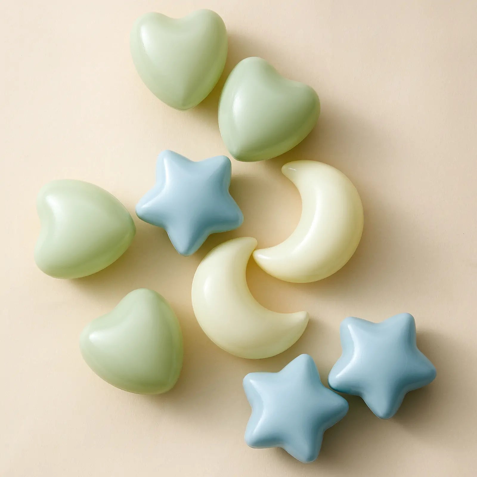 The Tiny Land® Green Adventure 3-in-1 Play Tunnel & Fun-Shapes Ocean Ball Set features pastel blue stars, yellow moons, and green hearts for sensory play, arranged on a light beige background.