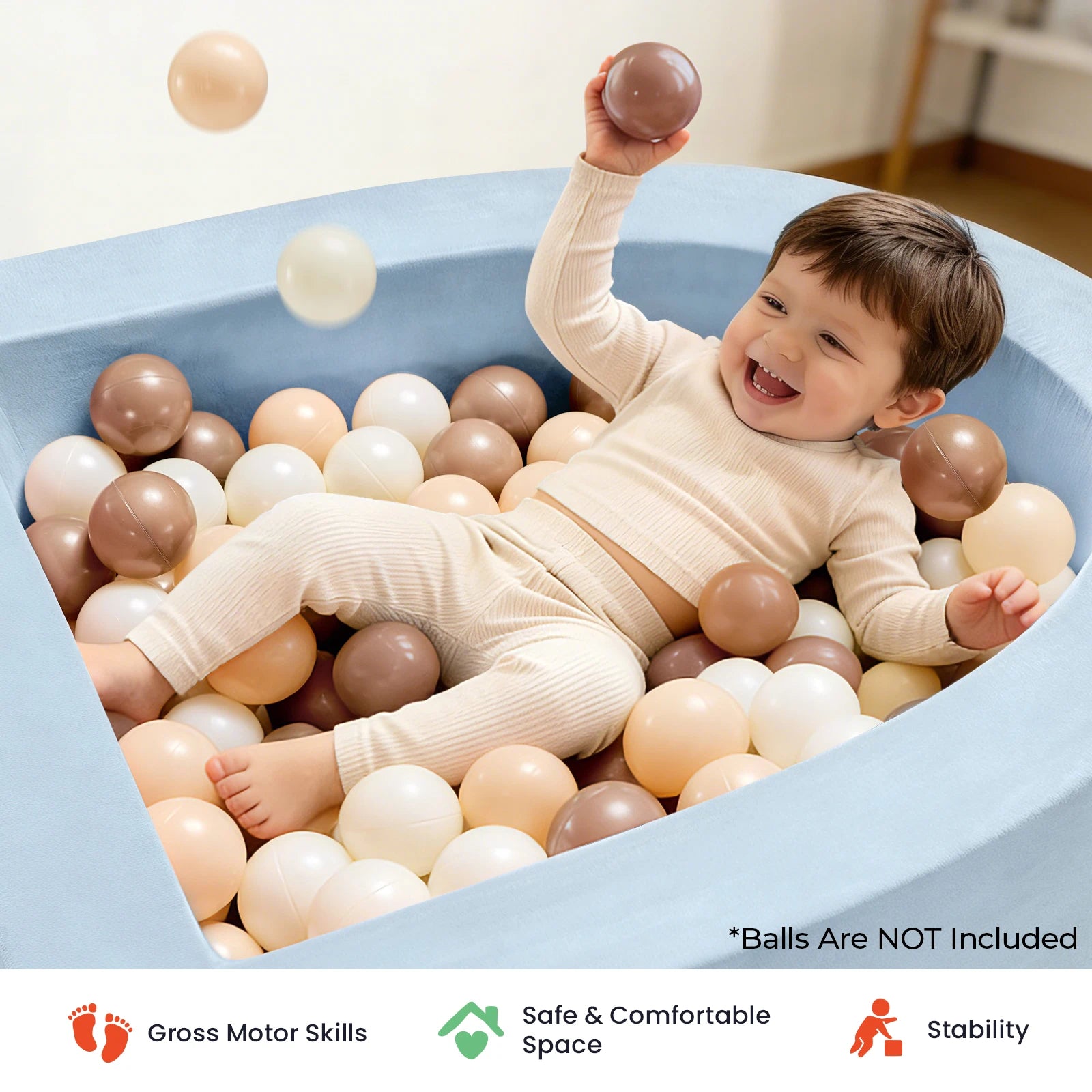 A happy toddler in cozy cream pajamas enjoys sensory play in the Tiny Land® PlayNest Soft Foam Ball Pit (balls not included), featuring a stylish light blue design perfect for any playroom. Icons below highlight gross motor skill development, safety, comfort, and stability—making it an ideal addition from Tiny Land.|Blue