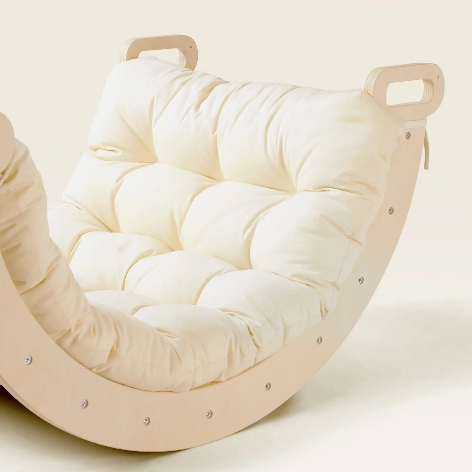 Inspired by the Tiny Land® 7-in-1 Montessori Climbing Set with Play Pad, this modern rocking chair by Tiny Land features a light wooden frame, plush cream tufted cushion, and cut-out handles on both ends of the frame.
