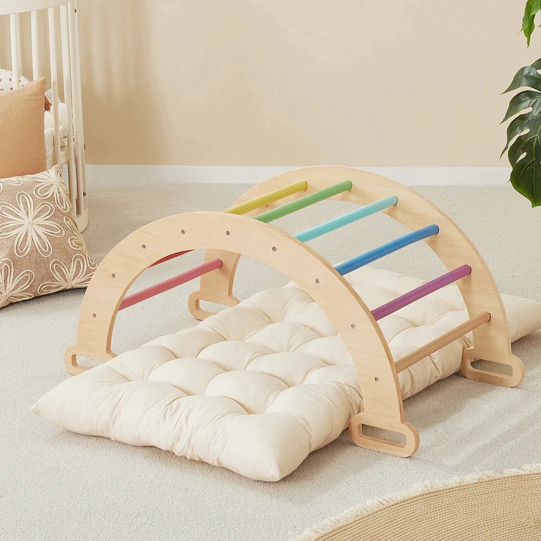 The Tiny Land Adventure Playground Gift Set—featuring a climbing set with pad, balance beam, and stepping stones—sits in a cozy, carpeted room with soft decor and a potted plant close by.