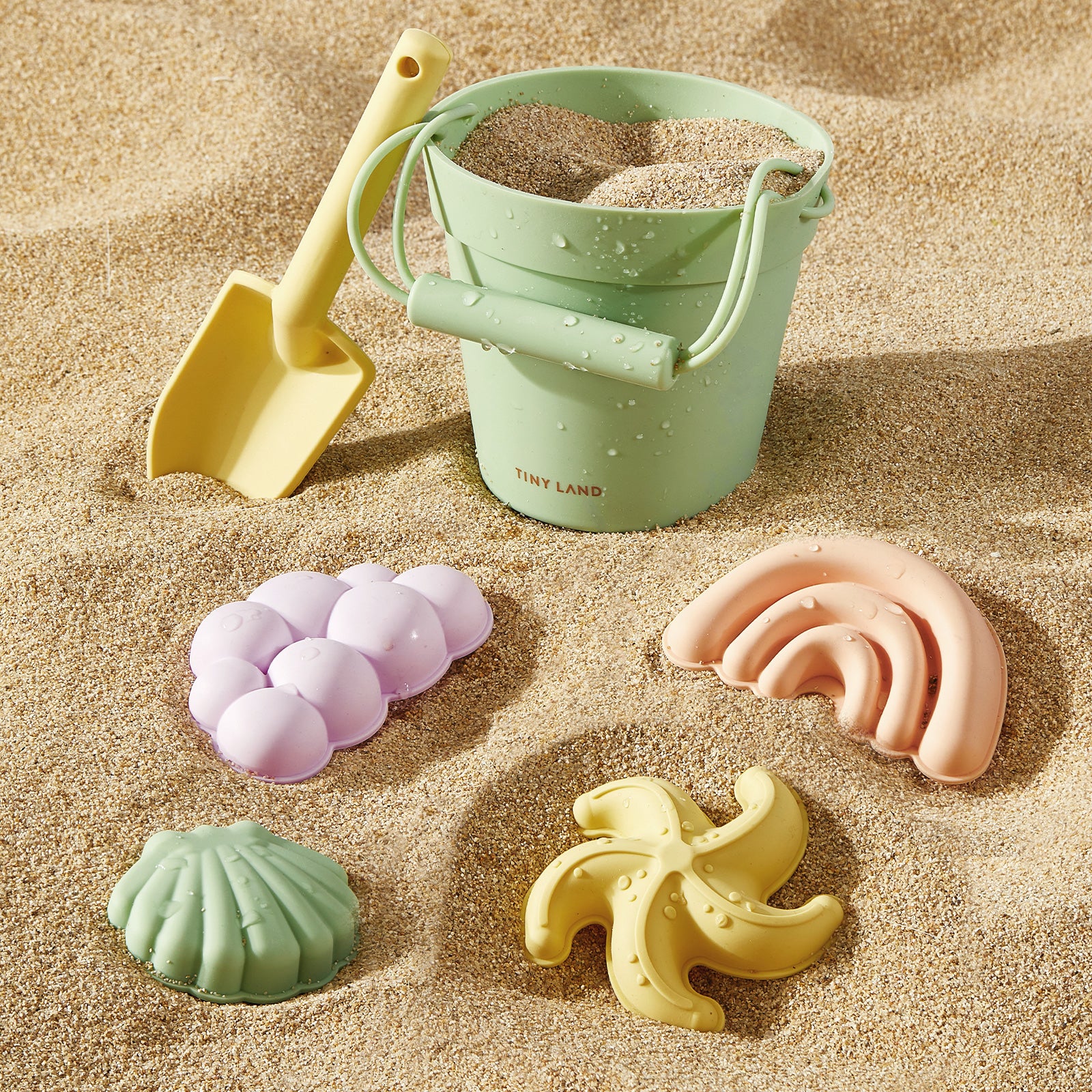 The Tiny Land® Baby Beach Tent & Sand Toy Set by Tiny Land includes a green bucket filled with sand, a yellow shovel, and four pastel-colored sand molds shaped like a shell, banana, grapes, and starfish—perfect for keeping your toddler entertained for hours of seaside fun.|Pink
