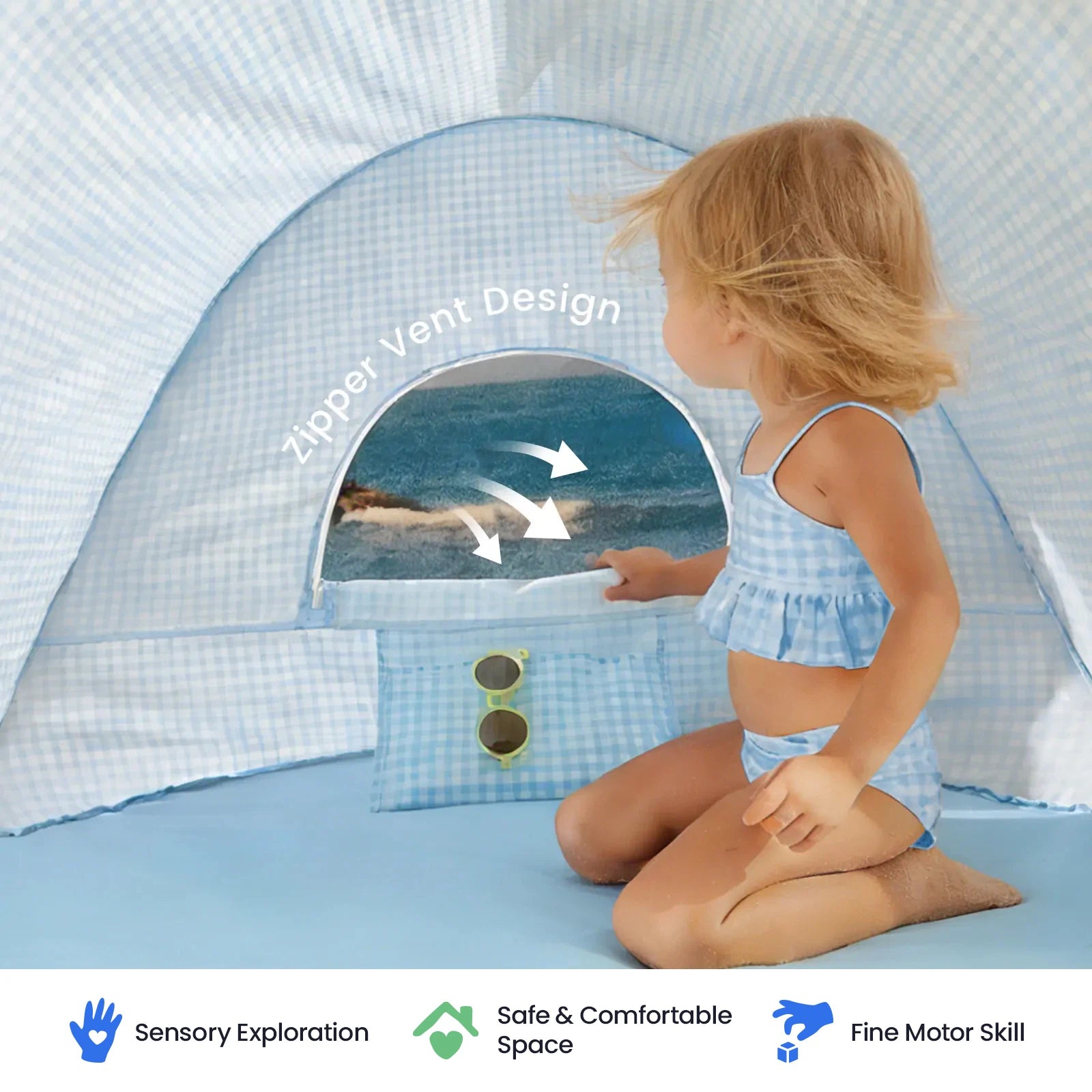 A young child in blue swimwear sits inside the Tiny Land® One-Stop Beach Toy & Tent Set—a small, blue-checkered tent by Tiny Land featuring UV protection, with a window revealing the beach outside. Icons below highlight sensory exploration, safety, and fine motor skill development.|Light Blue Gingham