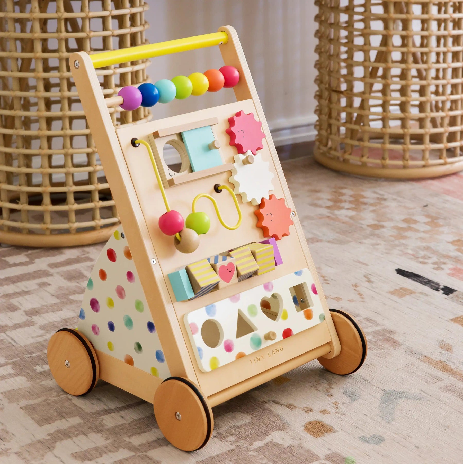 The Tiny Land All-Rounder Baby Playset — Baby Walker + Montessori Box (7-9 Months) features colorful beads, gears, shape sorters, four wheels, a yellow handle with pastel polka dots, and playful activities to support development|Rainbow
